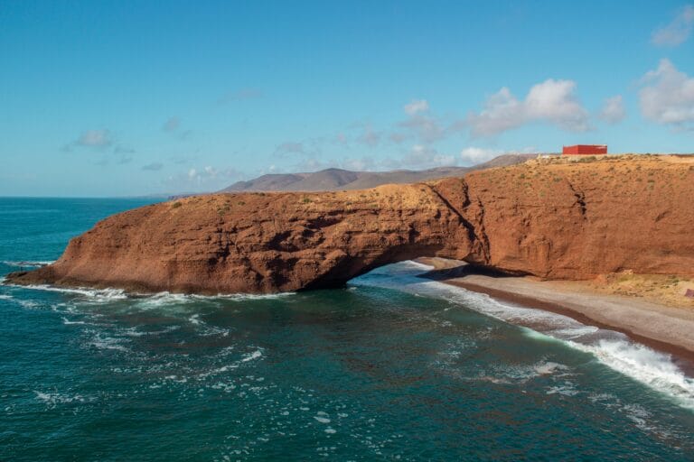 Legzira Beach Morocco is a breathtaking coastal escape known for its dramatic red rock arch and golden sands along the Atlantic.